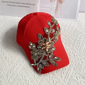 Detail der Goldfaden-Blumenstickerei und Strasssteine auf roter Baseballkappe