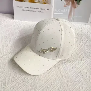 Close-up of white baseball cap with rhinestone embellishments and metal leaf detail