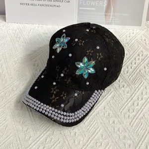 Détail d'une casquette en dentelle noire ornée de strass irisés et de perles blanches