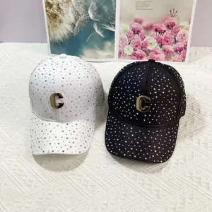 Dettaglio di cappellini da baseball con strass sfumati e logo C dorato in nero e bianco