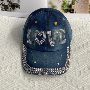 Gros plan du motif LOVE en strass scintillants sur une casquette en jean délavé style vintage