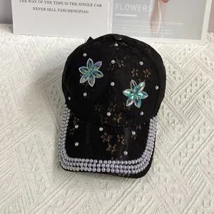 Détail de casquette de baseball en dentelle noire avec perles et fleurs en strass colorés