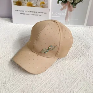 Detail of beige baseball cap with rhinestones and a delicate leaf-shaped gemstone brooch