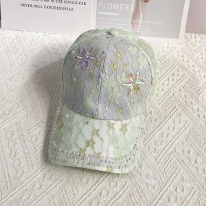 Détail de la casquette en dentelle vert clair avec bordure perlée et fleurs 3D