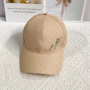 Close-up of beige baseball cap with gold rhinestones and leaf-shaped jewel embellishment