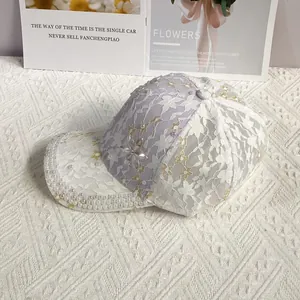 Détail de la casquette en dentelle avec bordure en perles et fleur en strass brillante