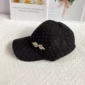 Detail of black rhinestone baseball cap featuring leaf metal buckle on white quilted fabric