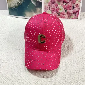 Dettaglio ravvicinato del cappello di strass rosa con lettera C in metallo dorato