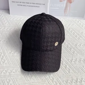 Close-up of houndstooth baseball cap with rhinestone M logo and metallic finish details