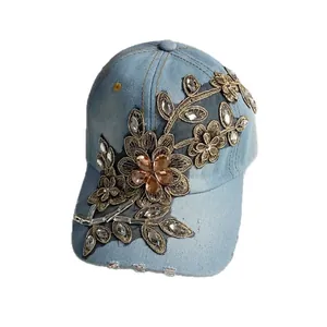 Blaue Denim-Baseballkappe mit goldener Blumenstickerei und Strasssteinen auf weißem Grund