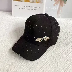 Detail of a black baseball cap featuring rhinestone leaf decor and white polka dots