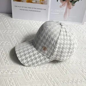 Detail of houndstooth baseball cap with gold emblem on a stylish decorative background