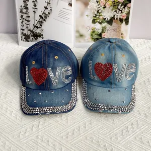Détail de casquettes de baseball en jean bleu avec motifs LOVE étincelants en strass