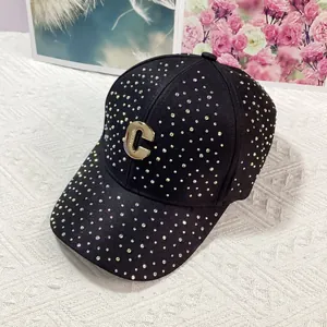 Dettaglio del berretto da baseball nero con strass colorati e logo C in metallo dorato
