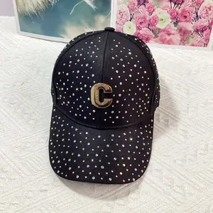 Dettaglio cappello nero con strass colorati e logo C in metallo dorato lucido