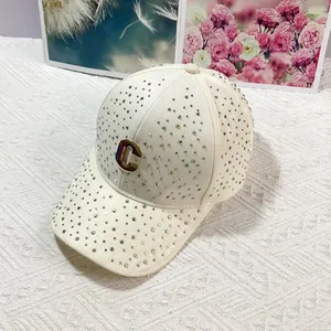 Dettaglio del cappellino crema con strass e logo C in metallo dorato sul davanti