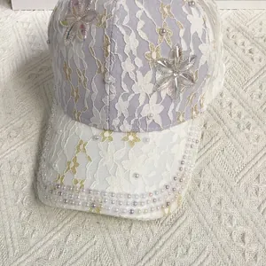 Détail de la casquette violette en dentelle avec broderie florale et perles décoratives