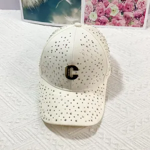 Dettaglio della cappellino bianco con strass colorati e logo C in metallo dorato