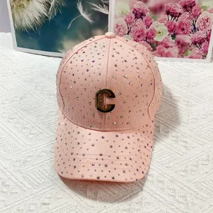 Vista dettagliata del cappellino rosa con strass, logo C dorato e finitura scintillante