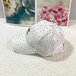 Dettaglio cappellino bianco con strass scintillanti e stemma con logo C in metallo dorato
