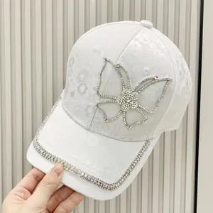 Close-up of white lace baseball cap featuring rhinestones butterfly and floral patterns