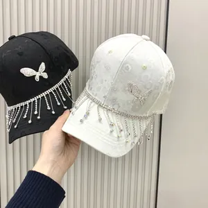 Close-up of rhinestone butterfly and hanging tassel details on fashionable baseball caps