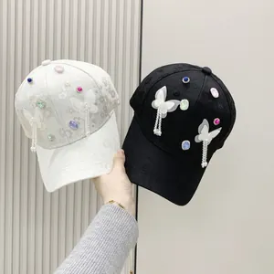 Detail of baseball caps with butterfly patches, pearls and crystal tassels for women
