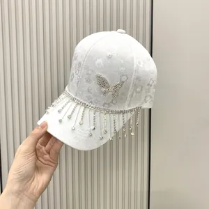 Macro shot of rhinestone butterfly and hanging tassels on a white jacquard baseball cap