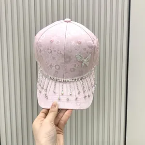 Pink rhinestone baseball cap featuring a diamond butterfly design and sparkling tassels