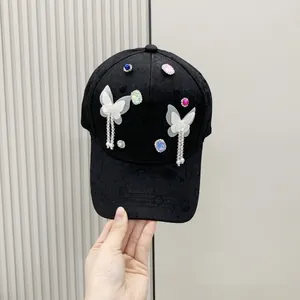 Detail of black baseball cap with rhinestone butterflies and hanging bead charms