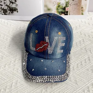 Détail des lettres LOVE en strass et motif lèvres rouges sur casquette en jean