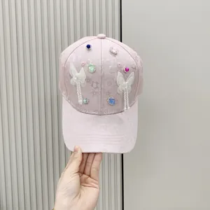 Close-up of light pink baseball cap with mesh bows, colorful rhinestones and pearl tassels