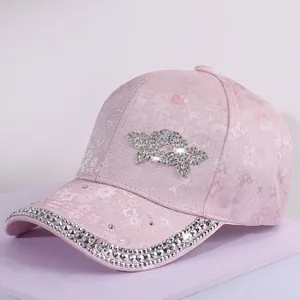 Close-up of pink satin baseball cap with floral embroidery and rhinestone butterfly detail