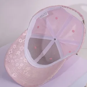 Detail of pink satin baseball cap featuring interior lining and 100% polyester care label