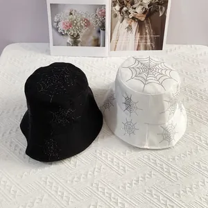 Detail view of cotton bucket hats in black and white with sparkling rhinestone spider webs