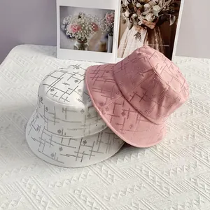 Detailansicht weißer und rosa Strass-Fischerhüte mit Blumenmustern auf dem Tisch