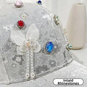 Dettaglio cappellino in pizzo con strass incastonati, perle e catenine di perline
