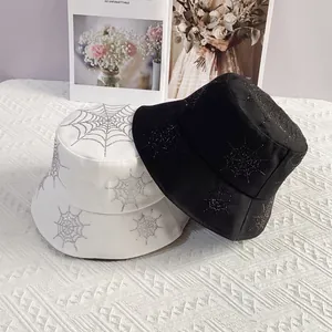 Close-up of sparkling rhinestone spider web patterns on black and white bucket hats