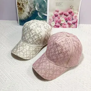 Detail von rosa und beigen Baseballkappen mit Strass-M-Mustern auf strukturiertem Stoff