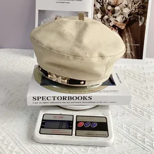 Detail showing the 87g lightweight beige beret with gold rhinestone butterfly buckle