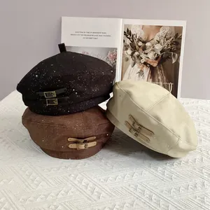 Detail view of retro beret hats with leather buckle decor in black, brown, and beige colors