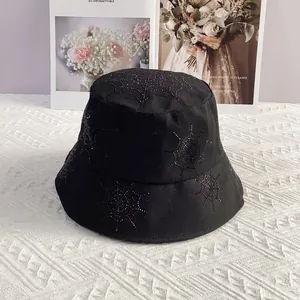 Detail of black bucket hat featuring rhinestone spider web design on white surface