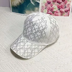 Detail von silbernen Strasssteinen und M-Buchstaben-Monogramm auf weißer Baseballkappe