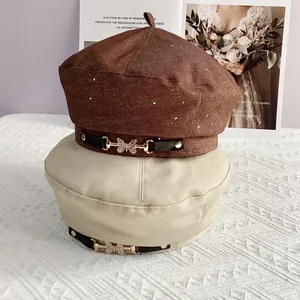 Close-up of sequin beret featuring a rhinestone butterfly buckle and leather trim