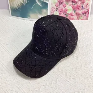 Detailansicht einer schwarzen Baseballkappe mit Strass-M-Muster auf weißem Stoffgrund