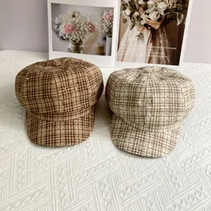 Detailed view of plaid newsboy hats featuring sparkling rhinestones on checkered fabric