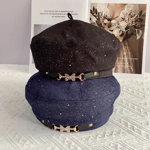 Detail of cotton berets in black and navy featuring rhinestone butterfly buckles