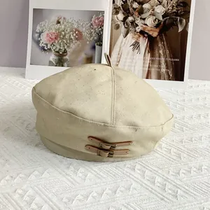 Close-up of a beige beret with glitter fabric and stylish brown leather buckle details