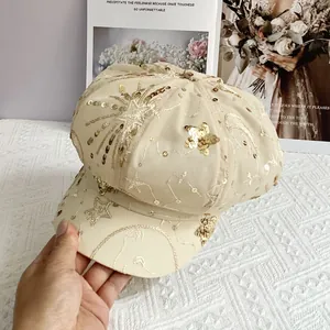 Close-up of beige newsboy cap featuring golden sequin star embroidery and mesh detail