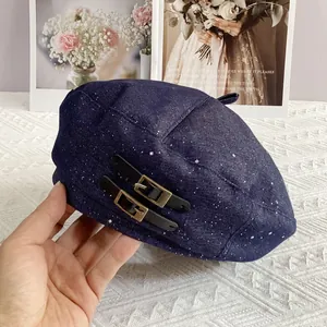 Detailed view of blue denim beret with silver glitter and black leather buckles